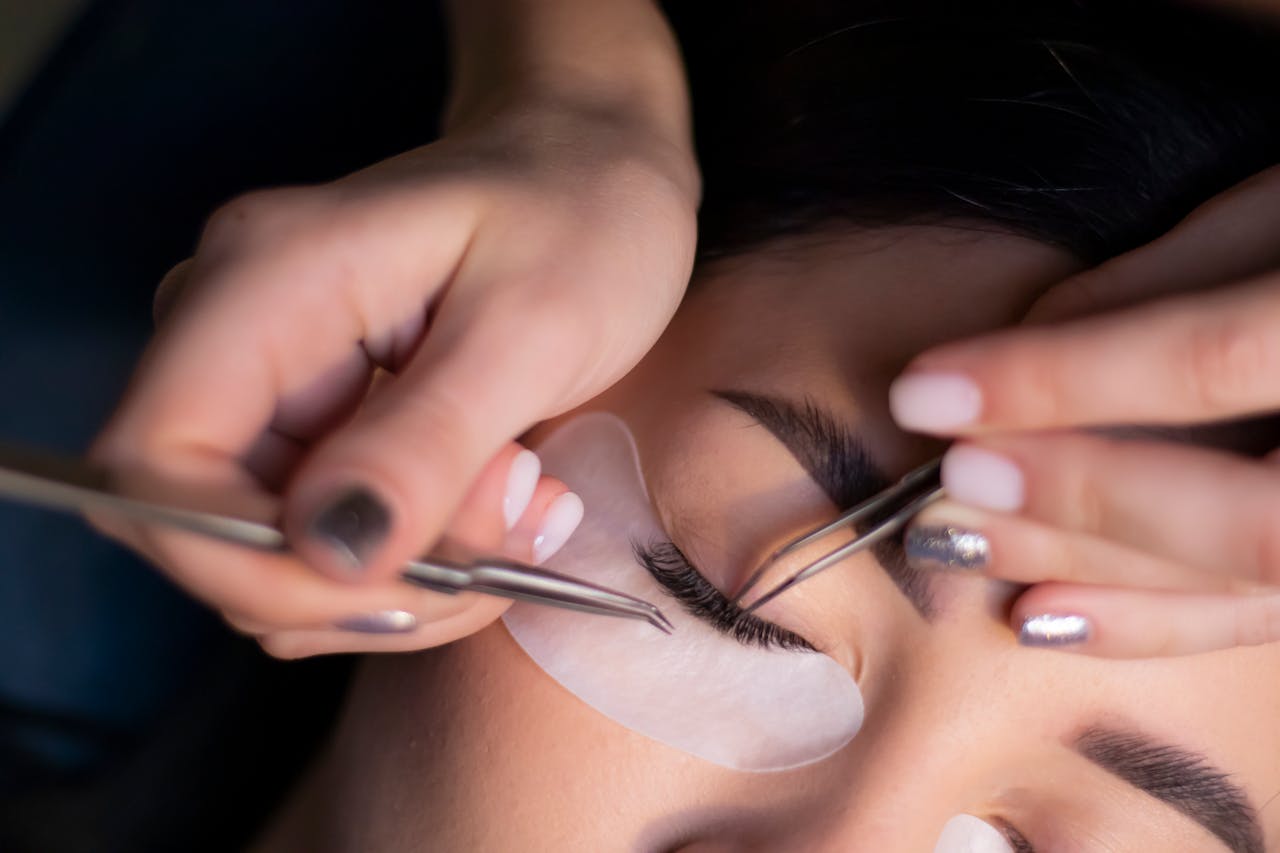 services-04 Detailed view of a beautician applying eyelash extensions to a womans eyes.