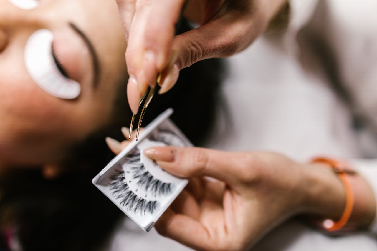 services-01 Close-up of applying false eyelashes with tweezers during a beauty treatment.