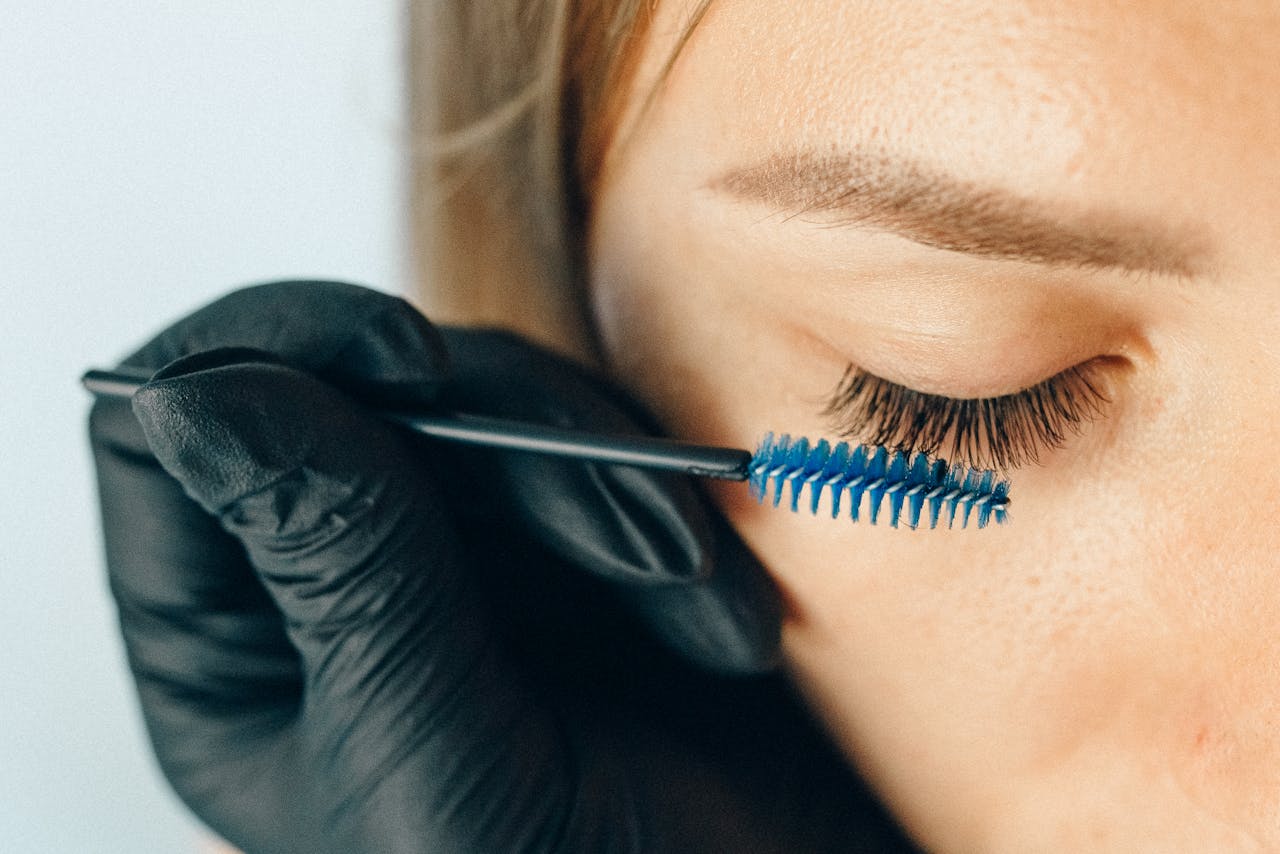 who-we-are A professional applying eyelash extensions using a blue applicator brush for a refined look.